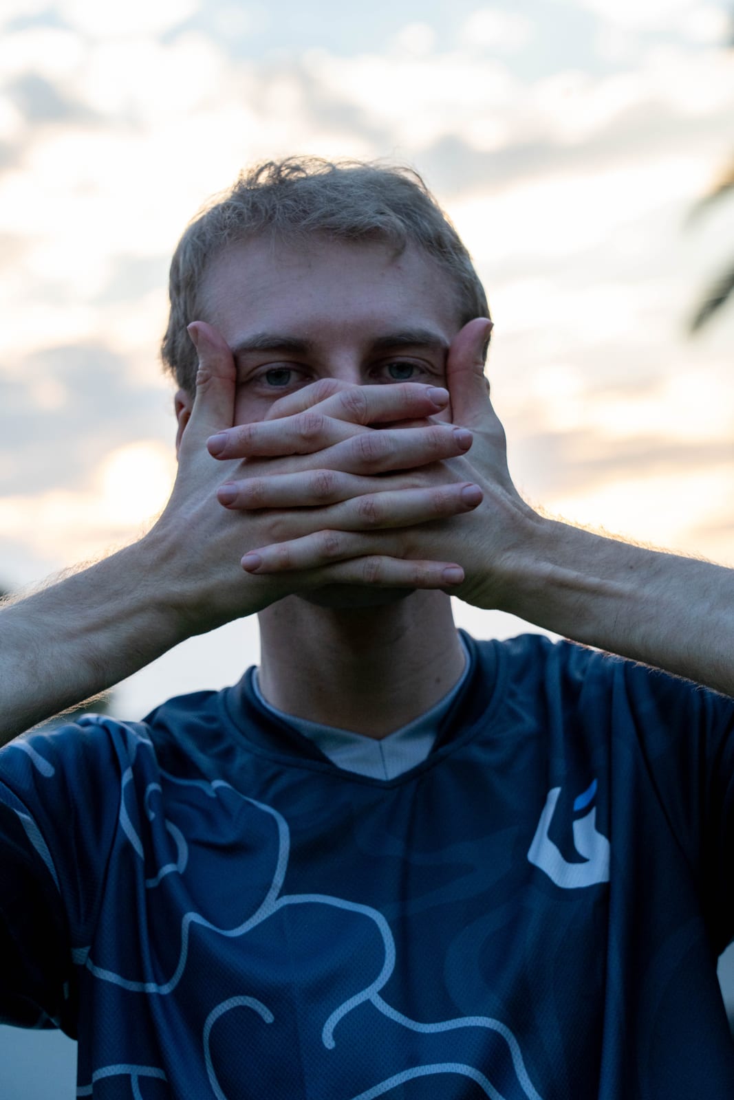 A player in a blue jersey with both hands laced over his face