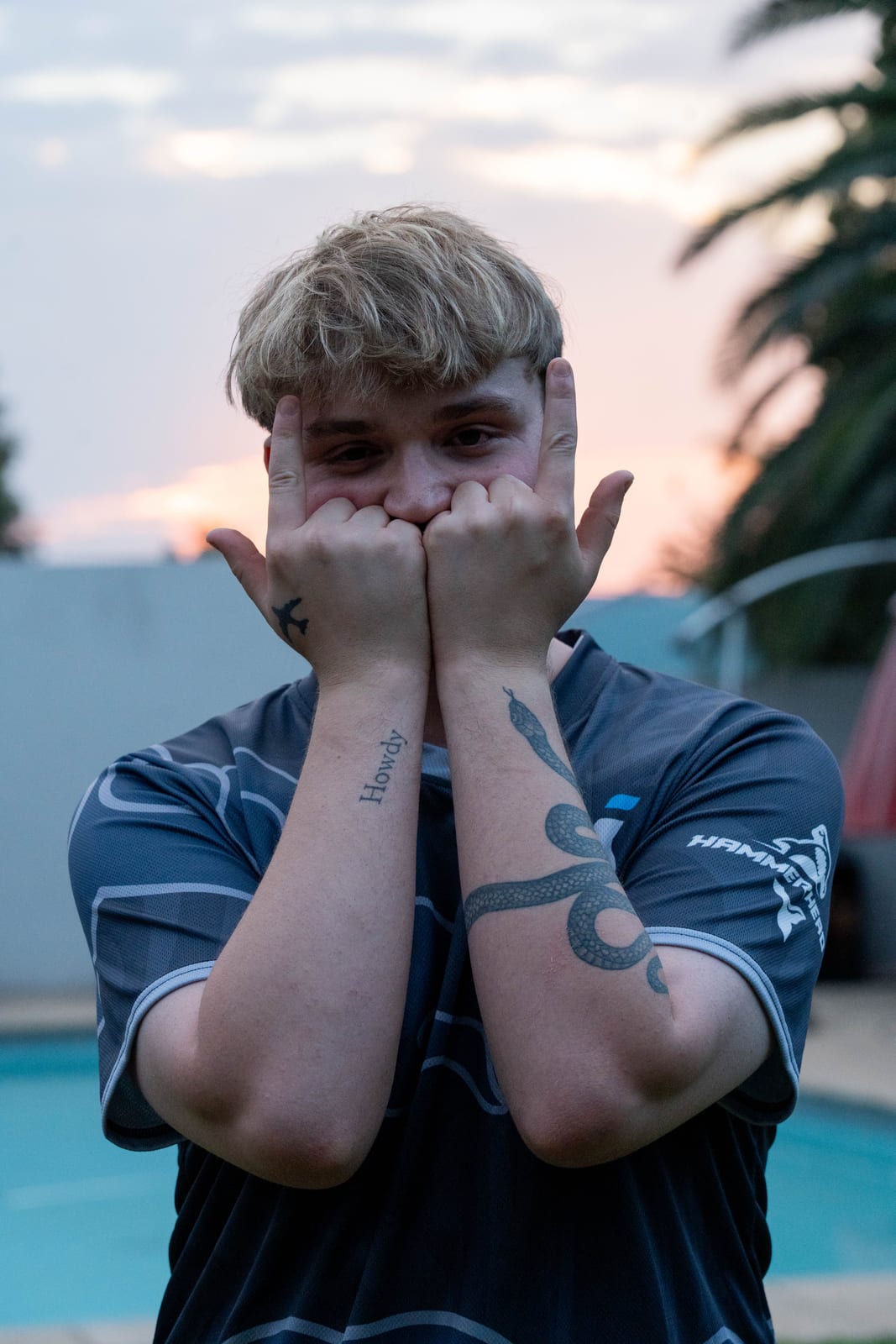 A player with tattooed forearms pressing his fists to his face at dusk