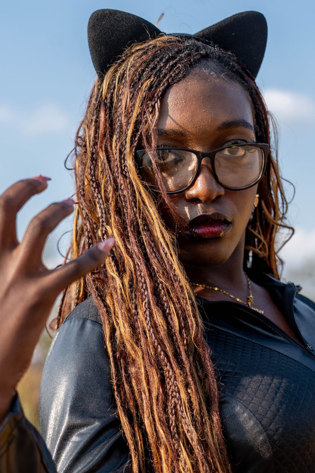 Portrait of a cosplayer in cat ears and glasses, one hand raised