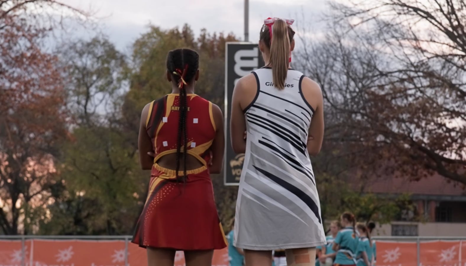 Still from School Clash: two players seen from behind, watching the court