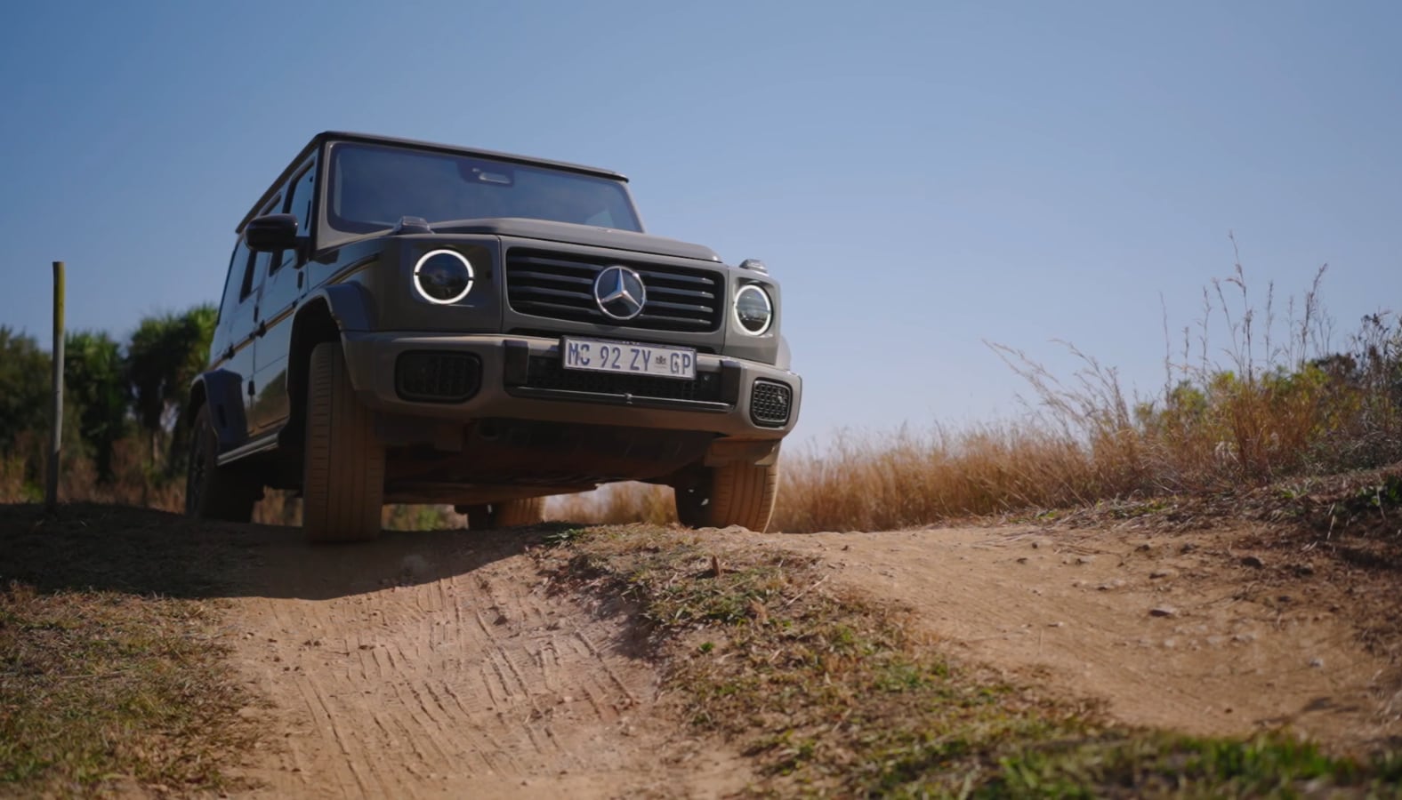 Still from Track Day: an off-road vehicle cresting a dirt climb under a blue sky