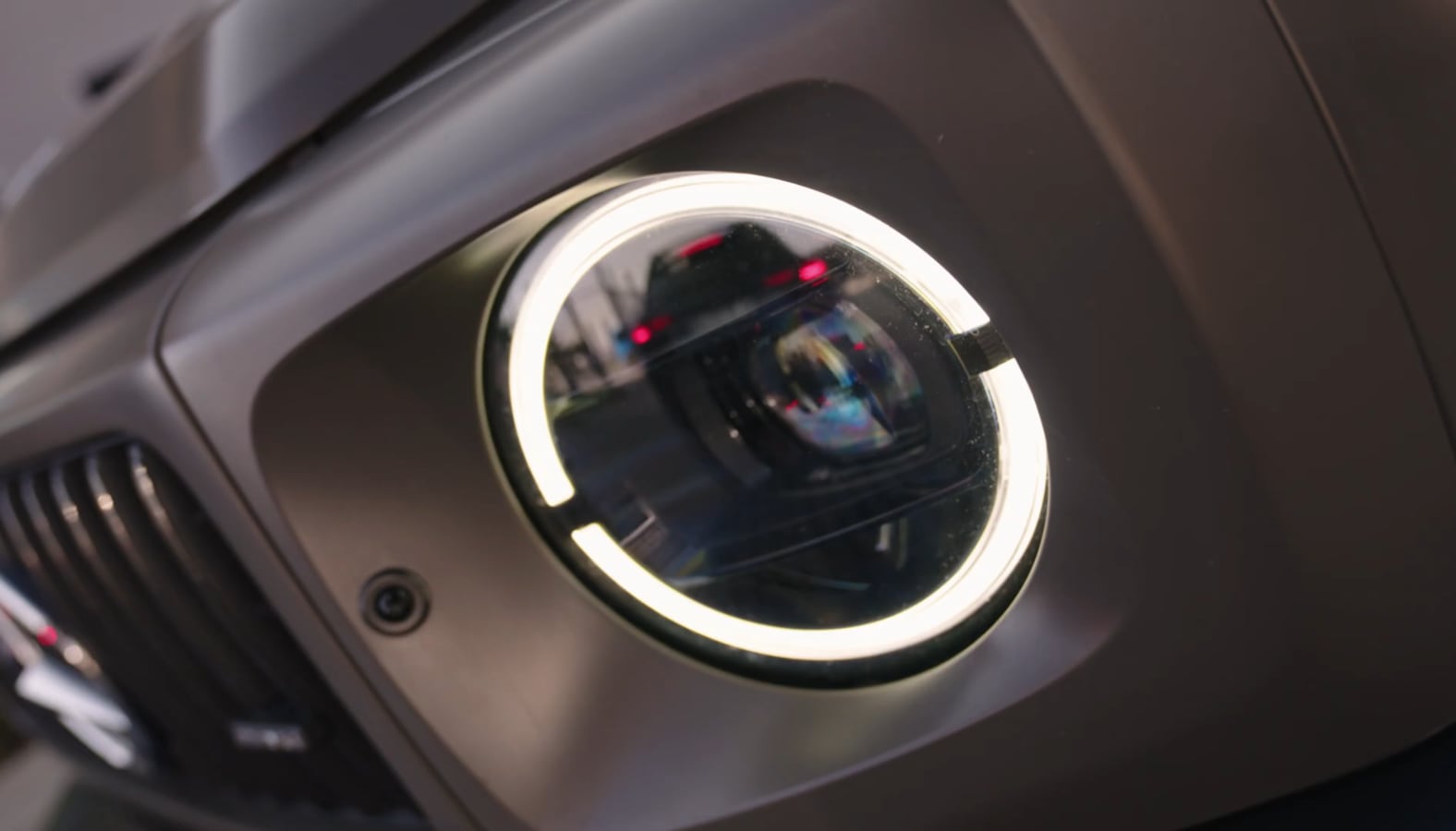 Still from Track Day: close detail of a round headlight with its ring lit